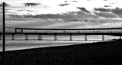 Bridge over river against cloudy sky