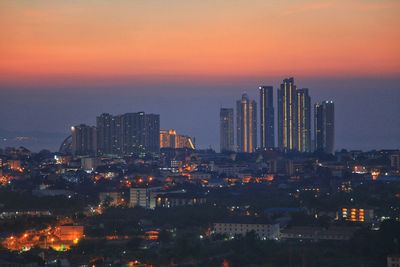 Illuminated buildings in city against sky during sunset