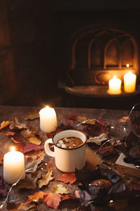 Cup of coffee with marshmallows on dark background with candle light