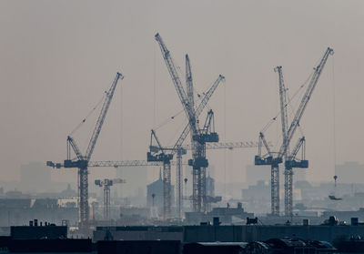 Cranes at construction site against sky