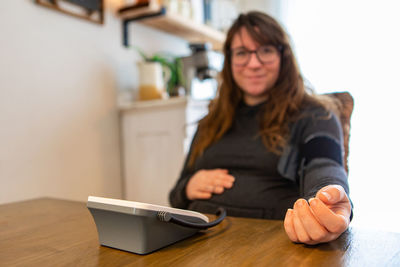 Portrait of smiling woman checking blood pressure at home