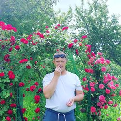 Portrait of man standing against flowering plants