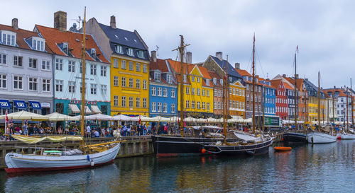 Boats moored in canal by city buildings against sky