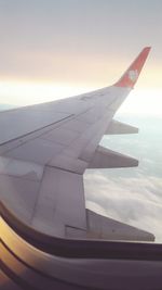 Airplane wing against sky during sunset