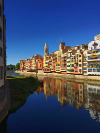 Reflection of buildings in lake against blue sky