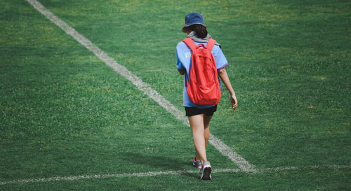 Rear view of woman walking on soccer field