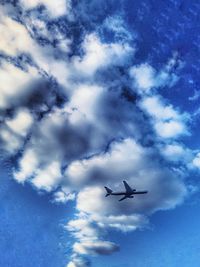 Low angle view of airplane flying against cloudy sky