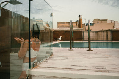 Reflection of woman in swimming pool by window