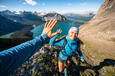 Hikers high fiving above kananaskis lake on sarrail ridge summit