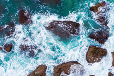 High angle view of waves splashing on rocks