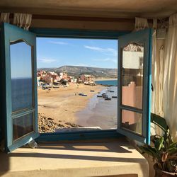 Panoramic view of sea and buildings seen through window