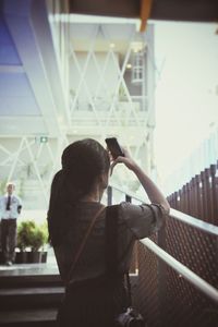 Rear view of woman photographing through smart phone