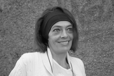 Close-up of smiling woman looking away while standing against wall