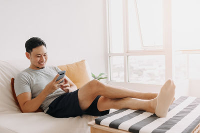 Young woman using laptop while sitting on bed at home