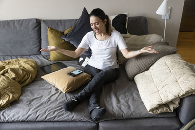Woman with disability gesturing while looking at smart phone sitting on sofa