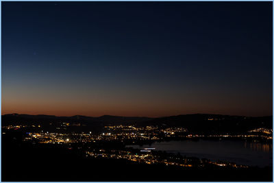 Illuminated cityscape against clear sky at night