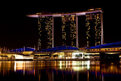 Illuminated bridge over river against sky at night