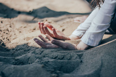 Low section of woman sitting on sand at beach