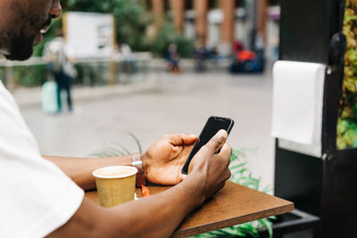 Midsection of man using mobile phone in city