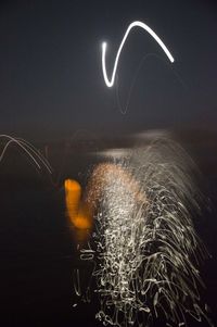 Digital composite image of light trails against sky at night