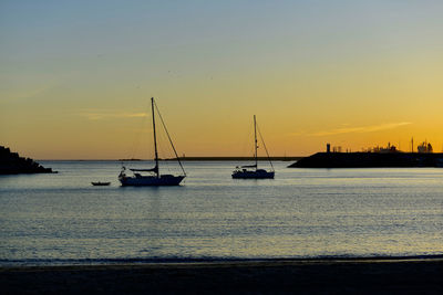 Silhouette sailboats sailing on sea against sky during sunset