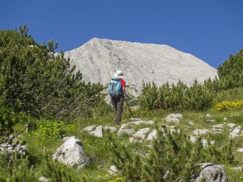 Rear view of woman standing on mountain against sky