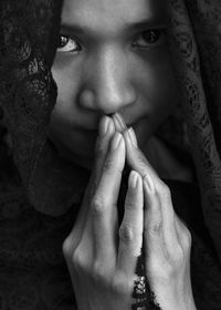 Close-up portrait of young woman wearing scarf with hands clasped