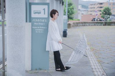 Portrait of young woman standing against building