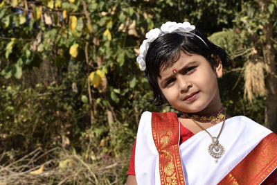 Portrait of girl in traditional clothing against plants