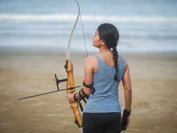 Woman holding umbrella while standing on beach