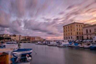 Boats moored in canal amidst buildings in city against sky