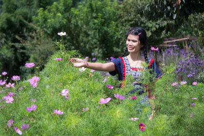 Woman with pink flowers against plants