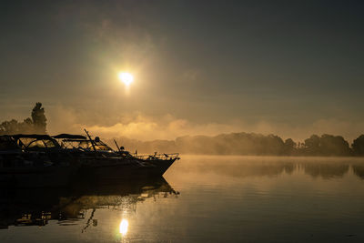 Fishing boat in sea against sky during sunset