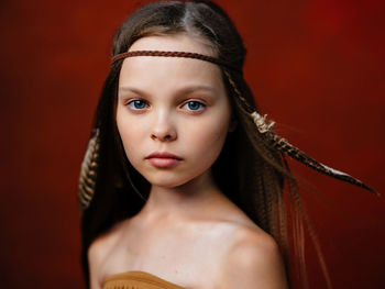 Close-up portrait of young woman against red background