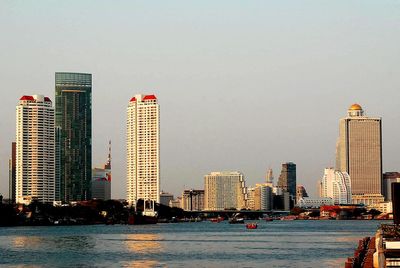 Sea by buildings against sky in city