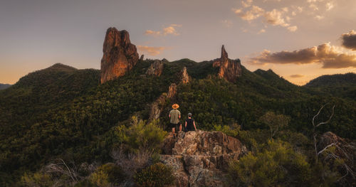 Rear view of man standing on mountain against sky during sunset