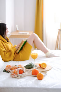 Young woman sitting on bed at home