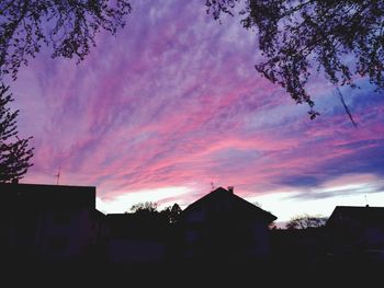 Silhouette houses against sky at sunset