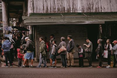 Group of people standing on street in city