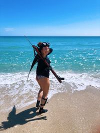 Rear view of woman standing at beach against sky