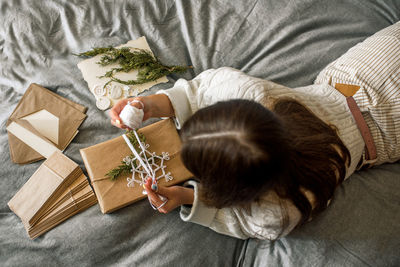 High angle view of girl with christmas presents lying on bed