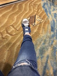 Low section of man wearing shoes on sand