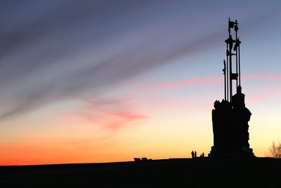 Silhouette monument on field against sky during sunset