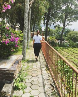 Woman walking on footbridge amidst trees