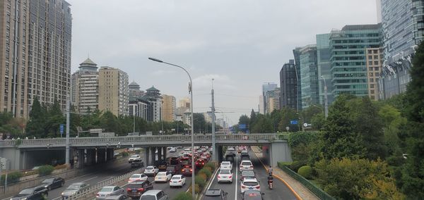 Traffic on road amidst buildings in city against sky