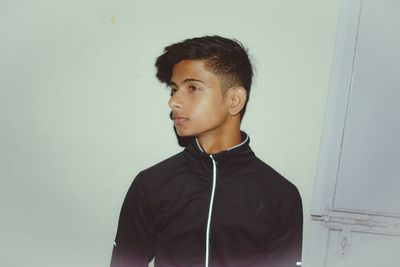 Thoughtful young man standing against wall