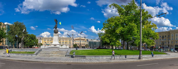 Statue by street against buildings in city against sky