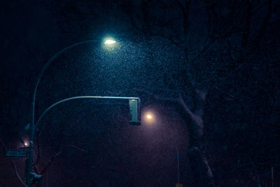 Illuminated street light against sky at night