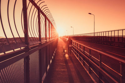 Bridge over street in city against sky during sunset