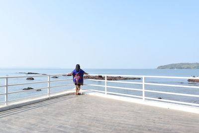 Rear view of woman looking at sea against clear sky